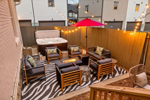 Fenced in back yard with fire pit, seating, and a hot tub.