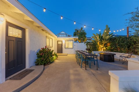 Evening patio with outdoor dining table, firepit, and tropical l