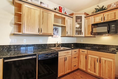 Efficiency kitchen with glass stove-top, microwave, dishwasher, and compact refrigerator (no oven).