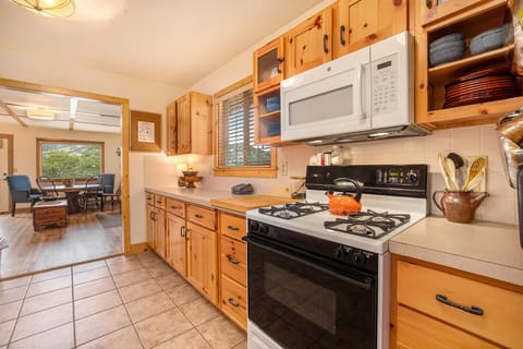 Kittery West Estes Park, Kitchen with gas stove/oven with microwave range hood, lots of counter and cabinet space, looking into living room at dining table with seating for 5.