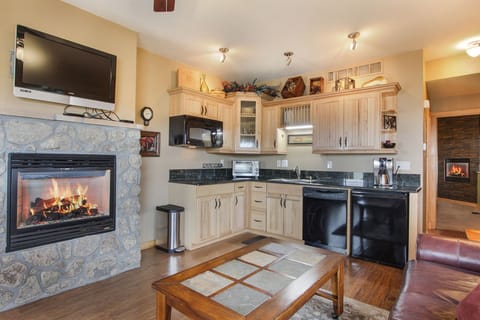Flat screen TV, gas stone fireplace and efficiency kitchen in the open living/dining area.