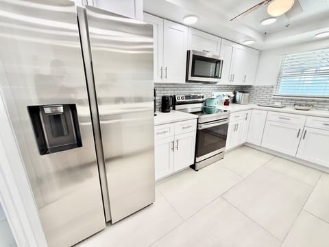 A sun-filled open kitchen with crisp white cabinetry, modern lighting, and a generous island that anchors the space and invites conversation.