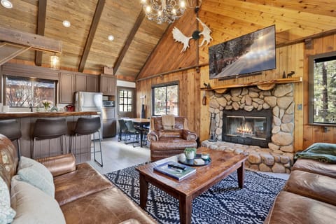 Cozy mountain living room with a stone fireplace, comfy seating, and smart TV—perfect for relaxing evenings, movie nights, and warm cabin vibes after outdoor adventures.