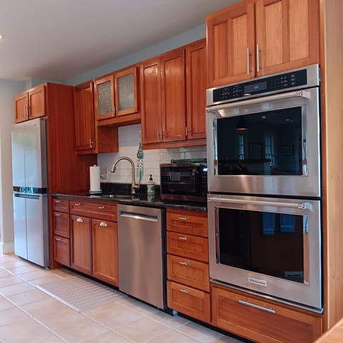 Double gas ovens . Cabinets are heavily stocked with dishware and glasseware.