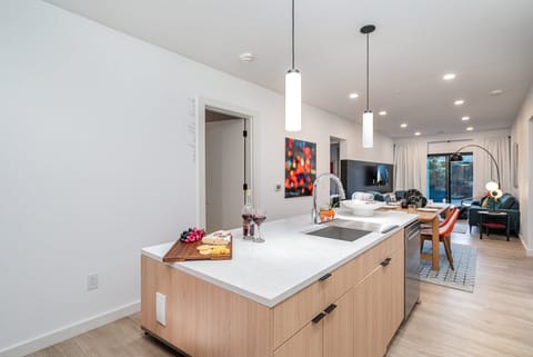 The fully equipped modern kitchen features culinary essentials, stainless steel appliances, and island bar seating.