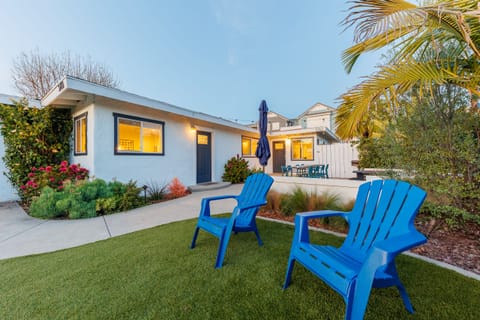Grassy backyard with blue Adirondack chairs and tropical landsca