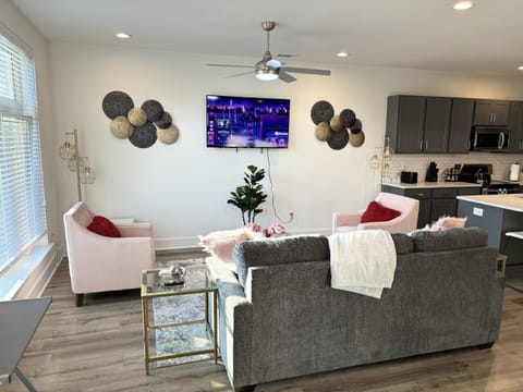 Stylish open-concept living area with modern decor, kitchen, and smart TV.