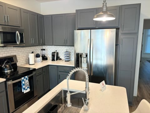 Modern kitchen with stainless steel appliances, gray cabinets, and subway tile backsplash.