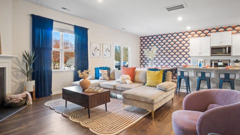Cozy living area with sectional sofa, patterned accent wall, and a kitchen bar. 