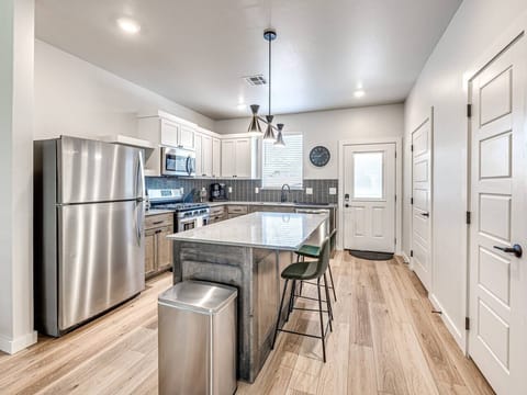 “Sleek and Functional: Modern kitchen with stainless steel appliances, a central island, and stylish bar stools.”