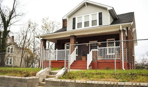 An inviting home with a charming chain link fence, steps leading to the front door. Nestled in a downtown location, this residence offers both convenience and allure—a perfect blend of urban living and cozy comfort.