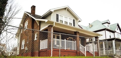 An inviting home, adorned with a charming chain link fence and front steps. Nestled in a prime downtown location, just a minute's drive away, this residence seamlessly combines urban living with cozy comfort—an ideal blend of convenience and allure.