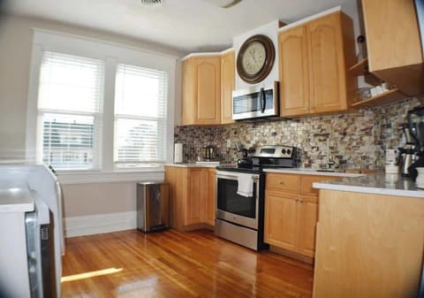 This kitchen is a timeless blend of function and style. A wall-mounted clock above the stove adds classic charm. The refrigerator and dishwasher stand as sleek companions, turning meal preparation into a tasteful and efficient experience.