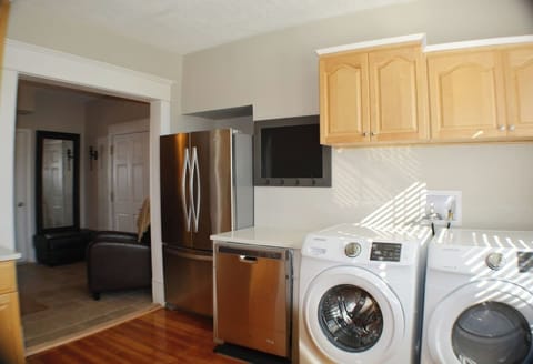Efficiency meets elegance in this kitchen oasis. Wooden cabinets exude warmth, framing a washer and dryer discreetly. A stainless steel refrigerator and dishwasher stand as modern marvels.