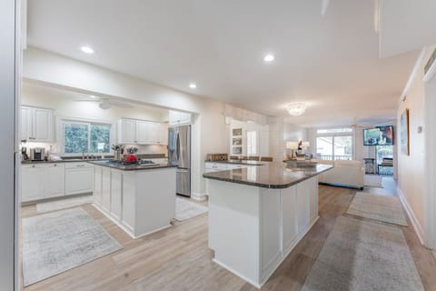 A modern kitchen with white cabinets, a built-in oven, a gas stove, and a large granite island.