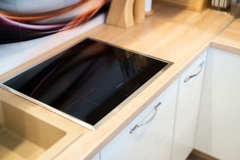 A close-up of an induction cooktop with a sleek black surface, blending seamlessly with the kitchen design.

