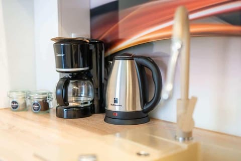 A close-up of a coffee station featuring a black kettle and coffee maker on a wooden countertop.

