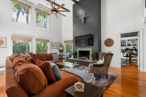 Relax in a light-filled living area featuring soaring ceilings and a cozy modern fireplace.