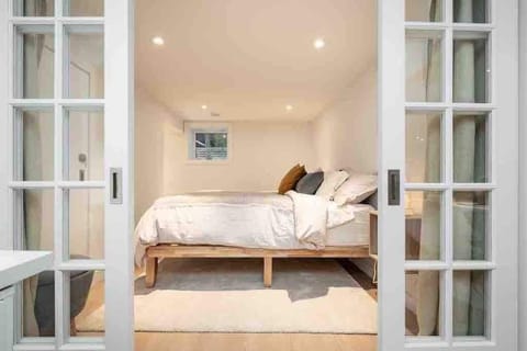 The cozy bedroom includes a king size bed, luxury bedding, a dresser and hangers