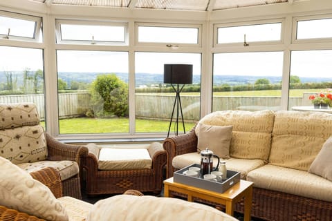 Conservatory with sofas and a small table with views out to the hills
