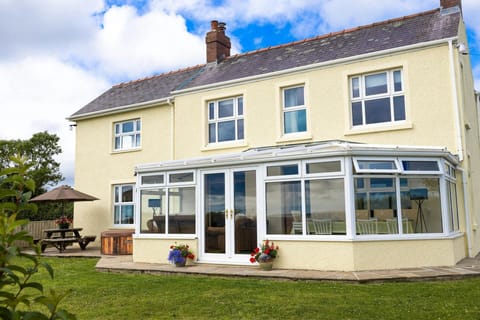 The back view of the house, with a conservatory, blues skies and the garden