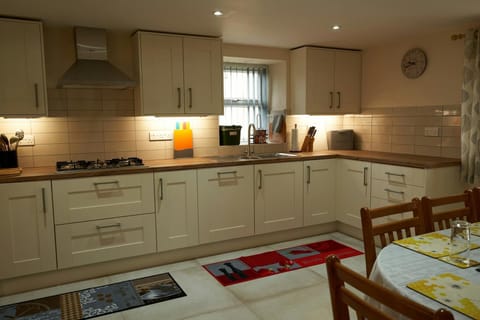 Kitchen cabinets, under cabinet lighting, hob, sink, dining table and chairs