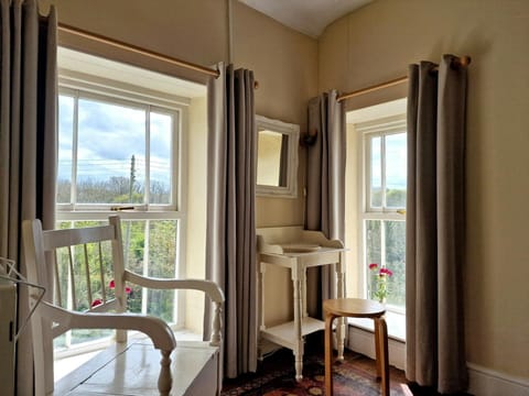 Double bedroom with views over the garden from two windows, chair, small unit with stool and mirror above