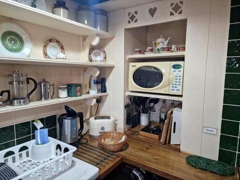 Kitchen area with shelving, microwave, toaster and kettle