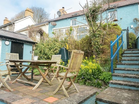 Patio area with wooden table and chairs, steps up to cottage