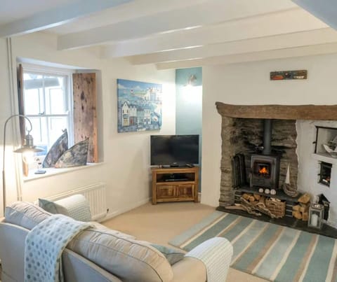 Living room with sofa, window with driftwood shutter, fireplace with woodburner