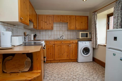 Kitchen with fridge freezer, washing machine, cooker, microwave, kettle and toaster