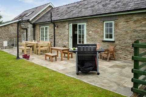 Paved patio with outdoor dining table and chairs, bbq and lawn