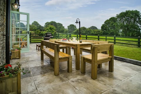 Paved patio with outdoor dining table and chairs, bbq and lawn