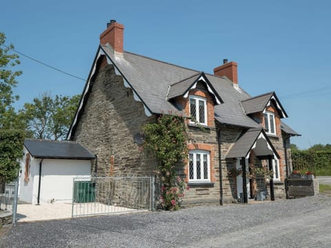 Outside view with gravel driveway, front porch and door, double metal gates