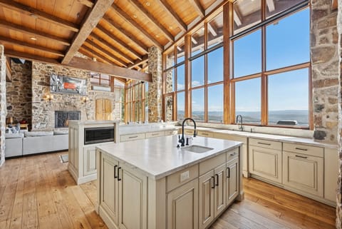 Luxury kitchen with farmhouse sink, stone accents, and vaulted wood ceilings.