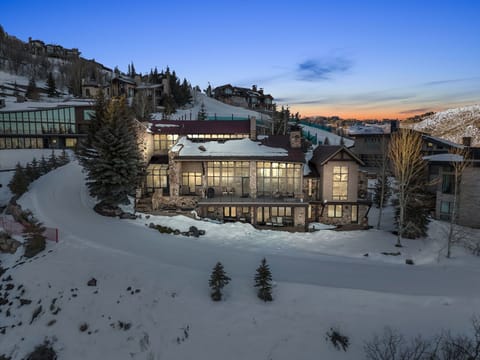 Luxury mountain home exterior at dusk with snow-covered slopes in Park City.