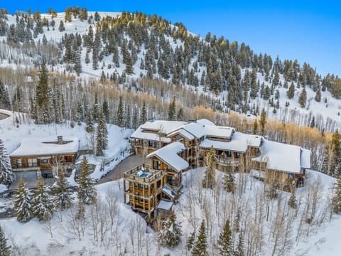 An external view of this luxury Park City vacation rental covered in snow, with a mountain view behind.