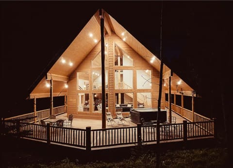 This breathtaking cabin glows at night, offering a spacious wraparound deck, a private hot tub, and the perfect setting for unforgettable evenings in the wilderness.