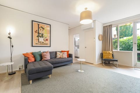 The living room is a fresh and vibrant space with retro look wall art, and bright throw pillows on the cosy chaise lounge.