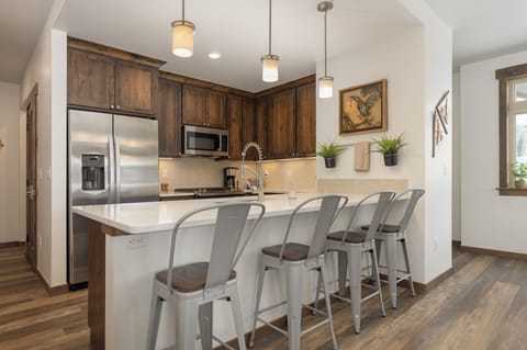 Your gourmet kitchen features rich wood cabinetry, stainless appliances, and a spacious island where you can gather for morning coffee or evening conversations.