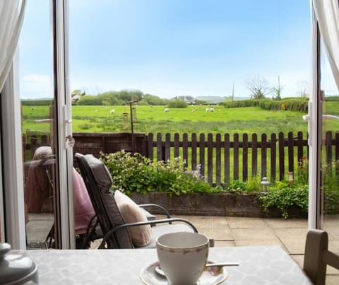 Patio doors leading to outside area with outdoor seating and view of fields with sheep