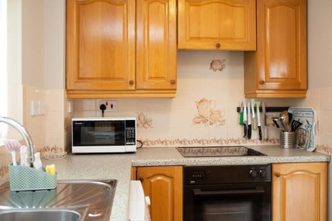 Wooden cabinets, oven, hob, microwave and utensils, magnetic knife rack