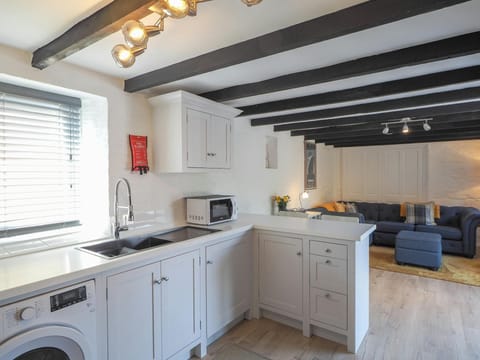 Kitchen area with washing machine, sink, microwave and sitting area in the background