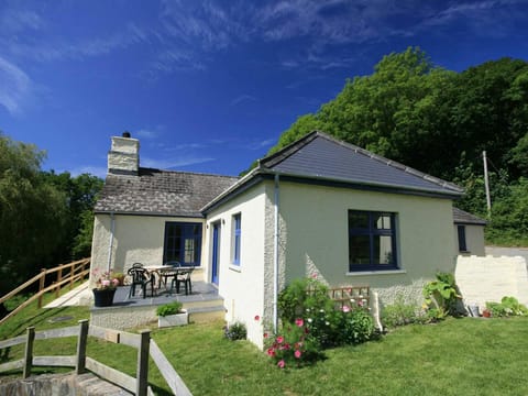 Penwaun from the back garden showing patio area with table and chairs, lawn and flowers