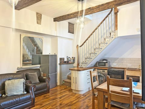 Open-plan room with leather sofa, dining table and staircase to mezzanine