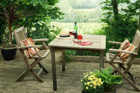 Decking area with wooden table and two chairs overlooking fields