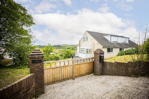 Front of the property with a retractable wooden gate and brick wall around the perimeter.