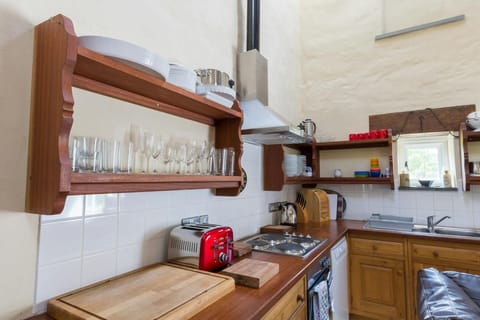 Kitchen: wooden shelves, cooker and hob, microwave and kettle, small window