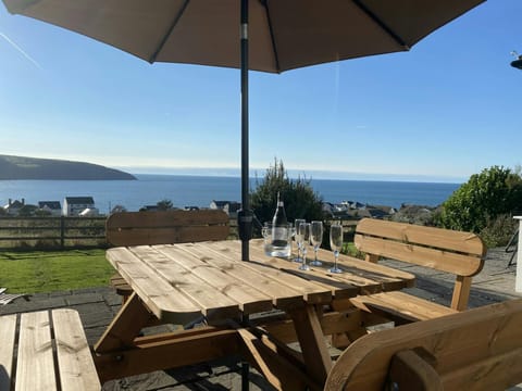 Garden table and benches with a parasol and bottle of wine and glasses