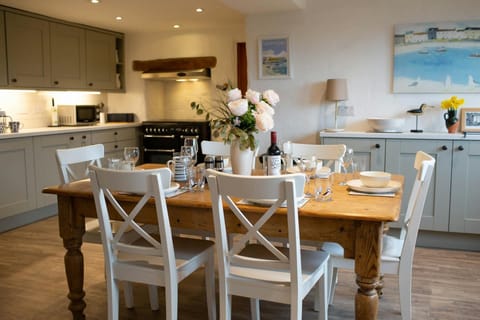 dining table to seat 6 laid for dinner with wine and flowers with kitchen behind and sideboard